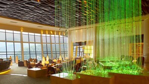 Un hall amplio con techos altos, ventanas grandes y un moderno candelabro.
