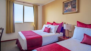 Habitació d'hotel amb dos llits, un quadre a la paret i una finestra amb cortines.