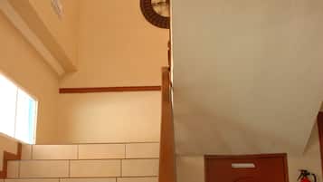 Una escalera con barandilla de madera, un extintor en la pared y una puerta cerrada.