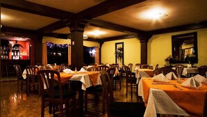 A restaurant with multiple tables and chairs, a bar area, and a warm interior ambiance.