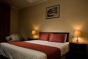 Ein Hotelzimmer mit einem Bett, zwei Nachttischlampen, einem Sessel und einem Bild an der Wand.