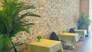 Un restaurante con paredes de piedra, plantas verdes y mesas con manteles amarillos.