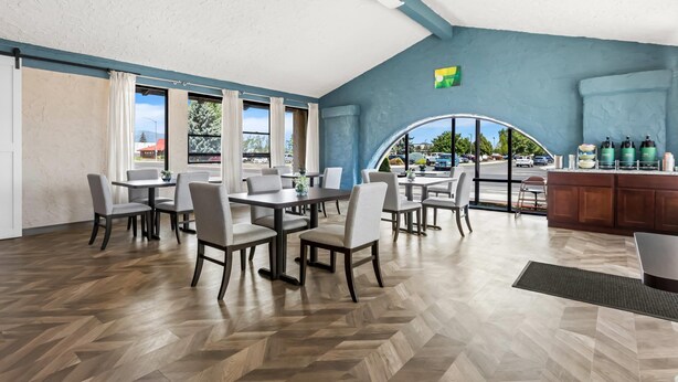 A spacious dining area with multiple tables and chairs, large windows, and a view of the parking lot. - Quality Inn Baker City (Baker City)