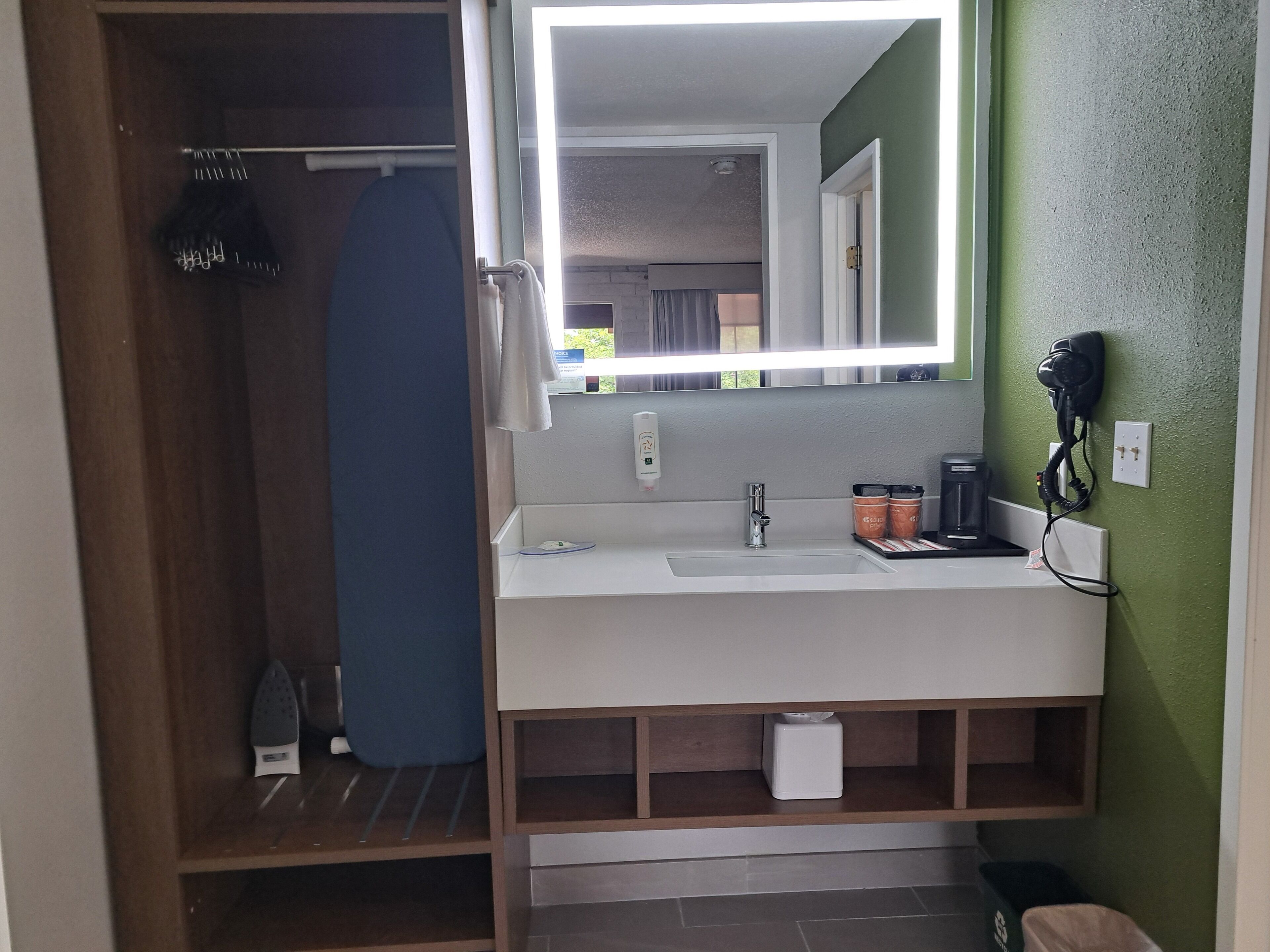 A bathroom with a white sink, a mirror, a shower curtain, and a coffee maker.