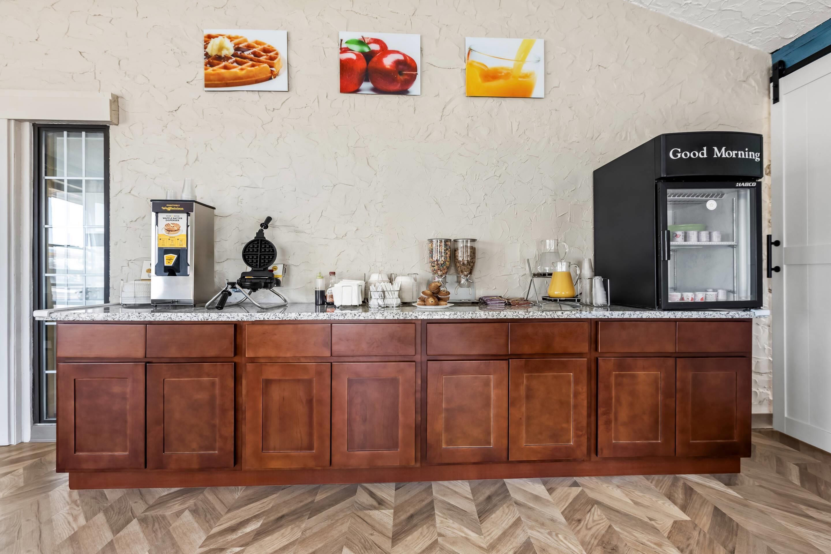 Una cocina equipada con una plancha para gofres, un refrigerador y una cafetera.