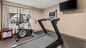 A room with a treadmill, a stationary bike, a television, and a window with curtains. - Quality Inn Baker City (Baker City)