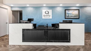 A reception desk with a marble top, a framed logo, and a desktop computer. - Quality Inn Baker City (Baker City)