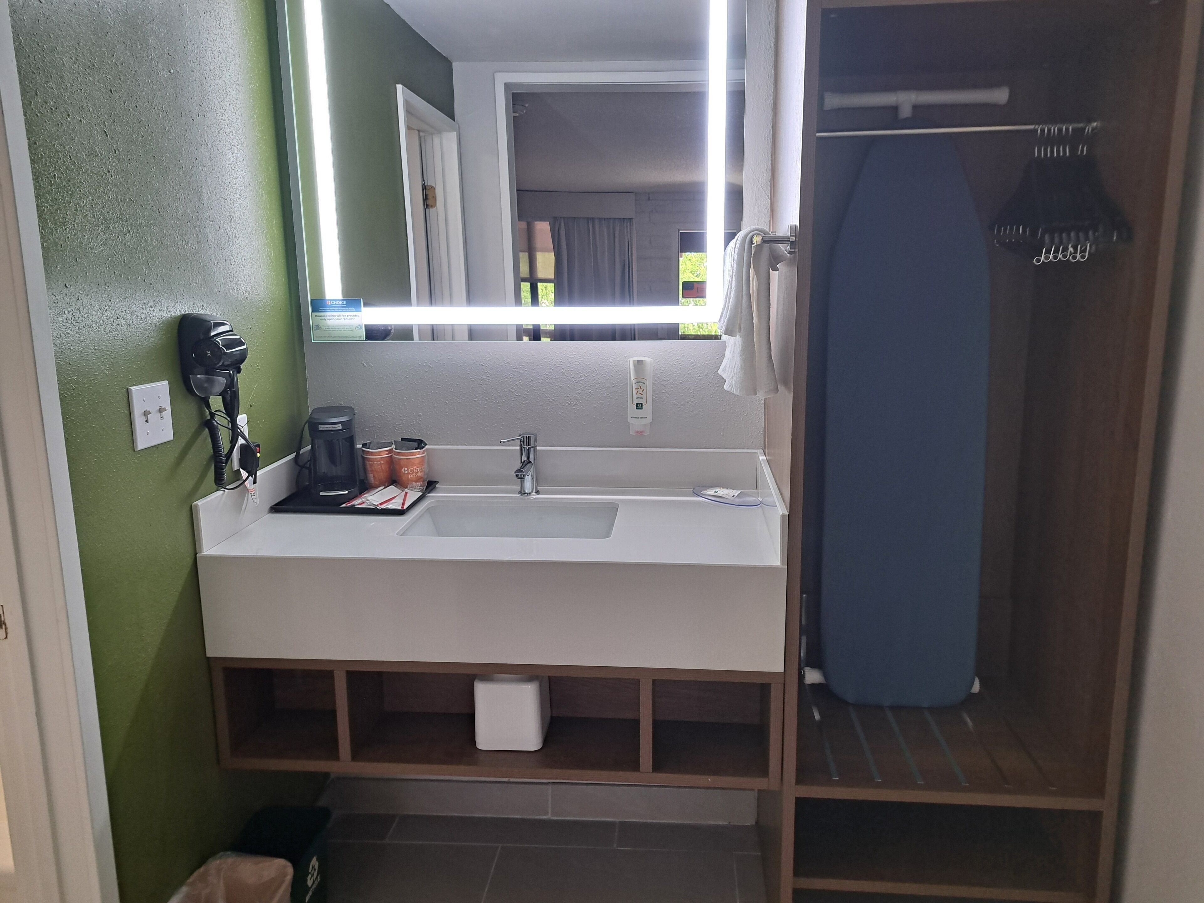 A bathroom with a white sink, a mirror, a hairdryer, and a shower curtain.