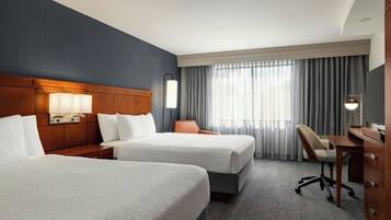 Ein Hotelzimmer mit zwei Betten, einem Schreibtisch und einem Stuhl.