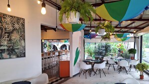 A modern cafe with glass tables, white chairs, and hanging plants. - Colours Oasis Resort ADULT ONLY (San José)