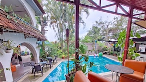 A pool area with lounge chairs and tables, surrounded by potted plants and a covered patio. - Colours Oasis Resort ADULT ONLY (San José)