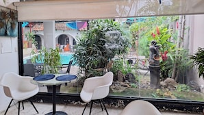 A glass-enclosed patio with a pool, white chairs, and a statue. - Colours Oasis Resort ADULT ONLY (San José)