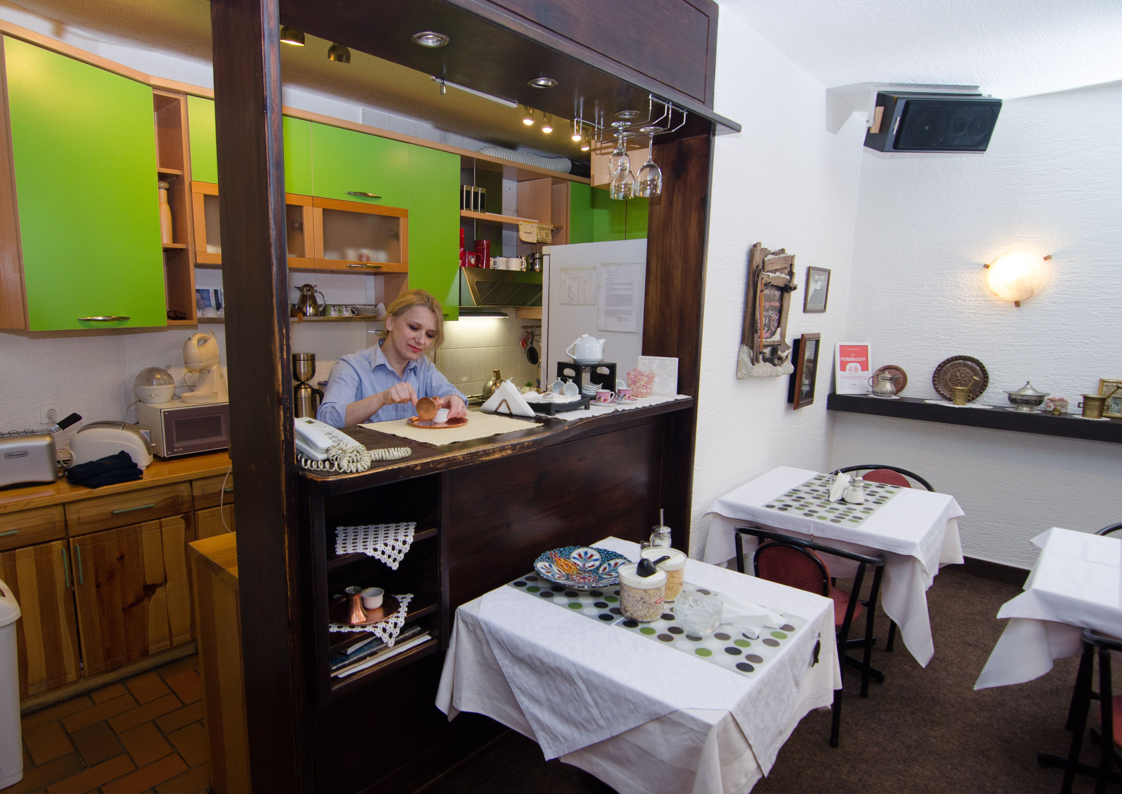 A restaurant interior with a counter, tables, and various kitchen appliances.