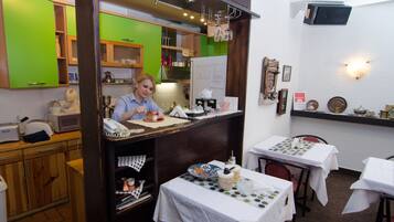 A restaurant interior with a counter, tables, and various kitchen appliances.