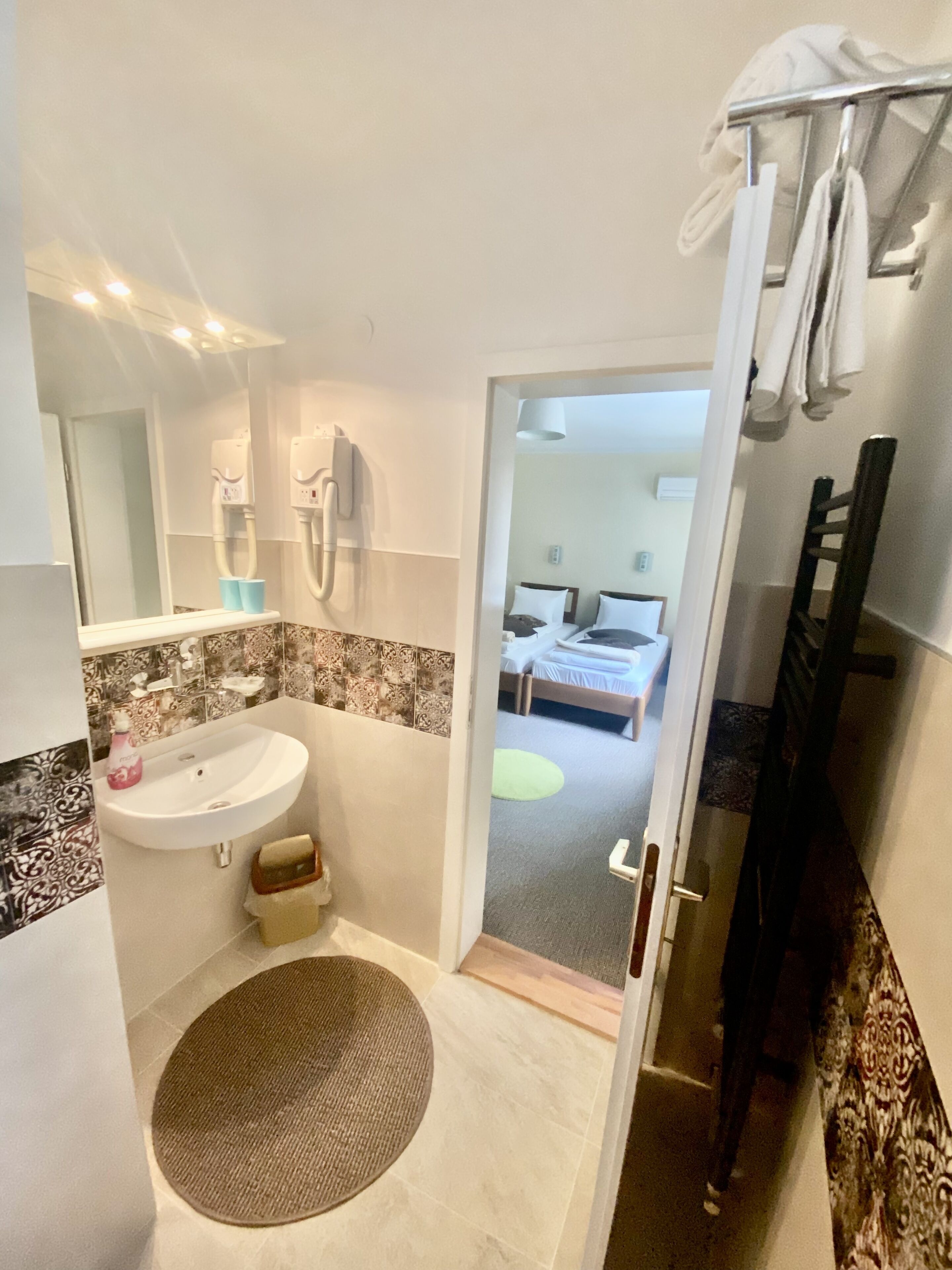 A modern bathroom with a sink, mirror, and towel rack.