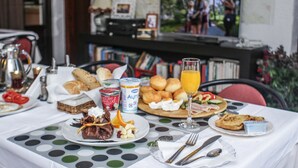 Une table de petit-déjeuner avec divers aliments, un téléviseur en arrière-plan et une nappe à pois.