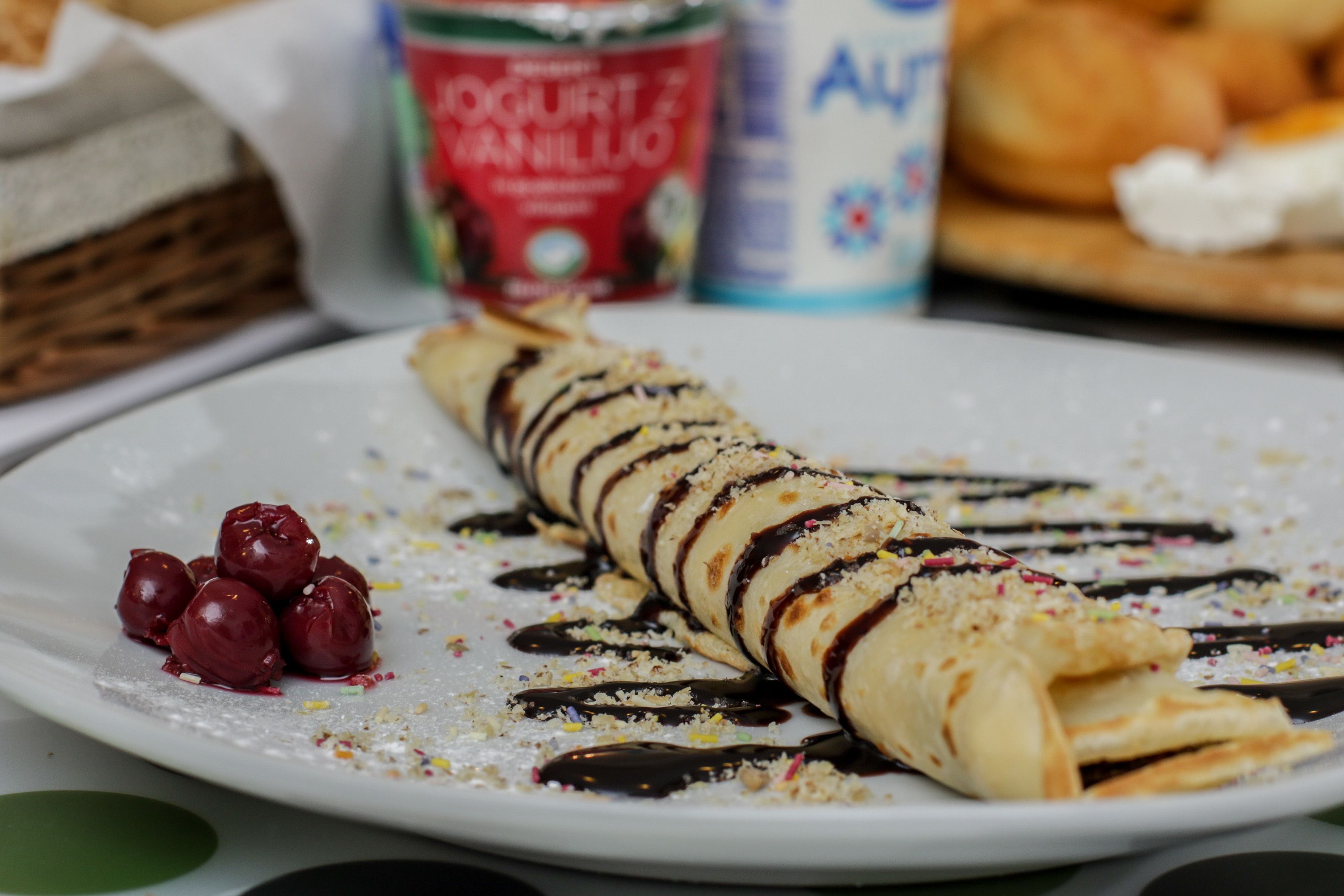 A dessert plate with a crepe, chocolate sauce, and berries.