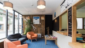 A modern interior with a seating area, a wooden accent wall, and a chalkboard menu. - Hotel Les Lanchers (Chamonix-Mont-Blanc)
