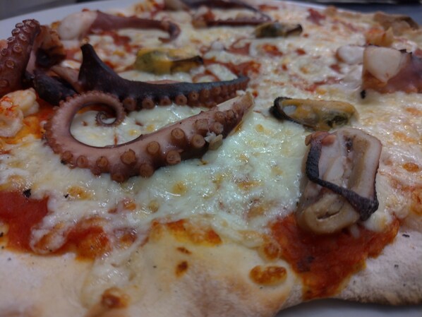A pizza with octopus tentacles, mushrooms, and cheese. - Hotel Les Lanchers (Chamonix-Mont-Blanc)