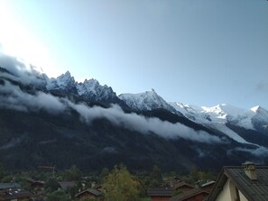 A mountain landscape with snow-capped peaks, a village with traditional houses, and a forested valley. - Hotel Les Lanchers (Chamonix-Mont-Blanc)