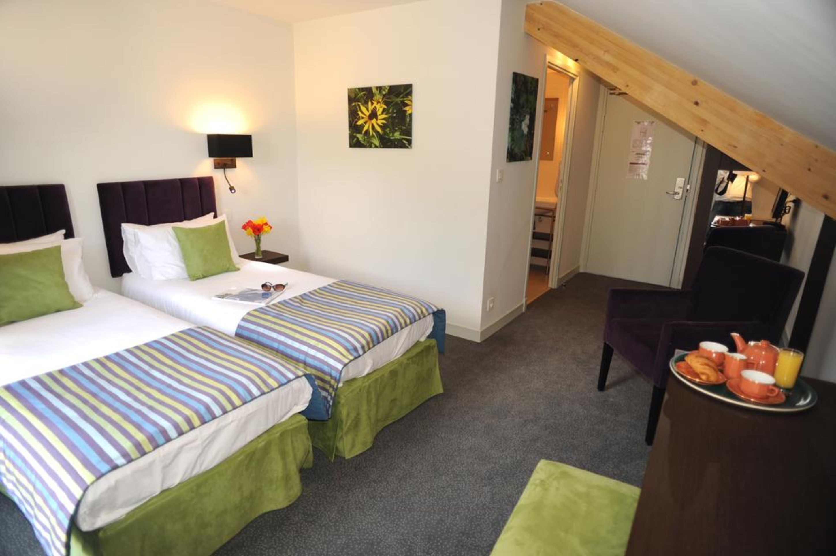 A hotel room with two beds, a desk with breakfast, and a staircase leading to an upper level.