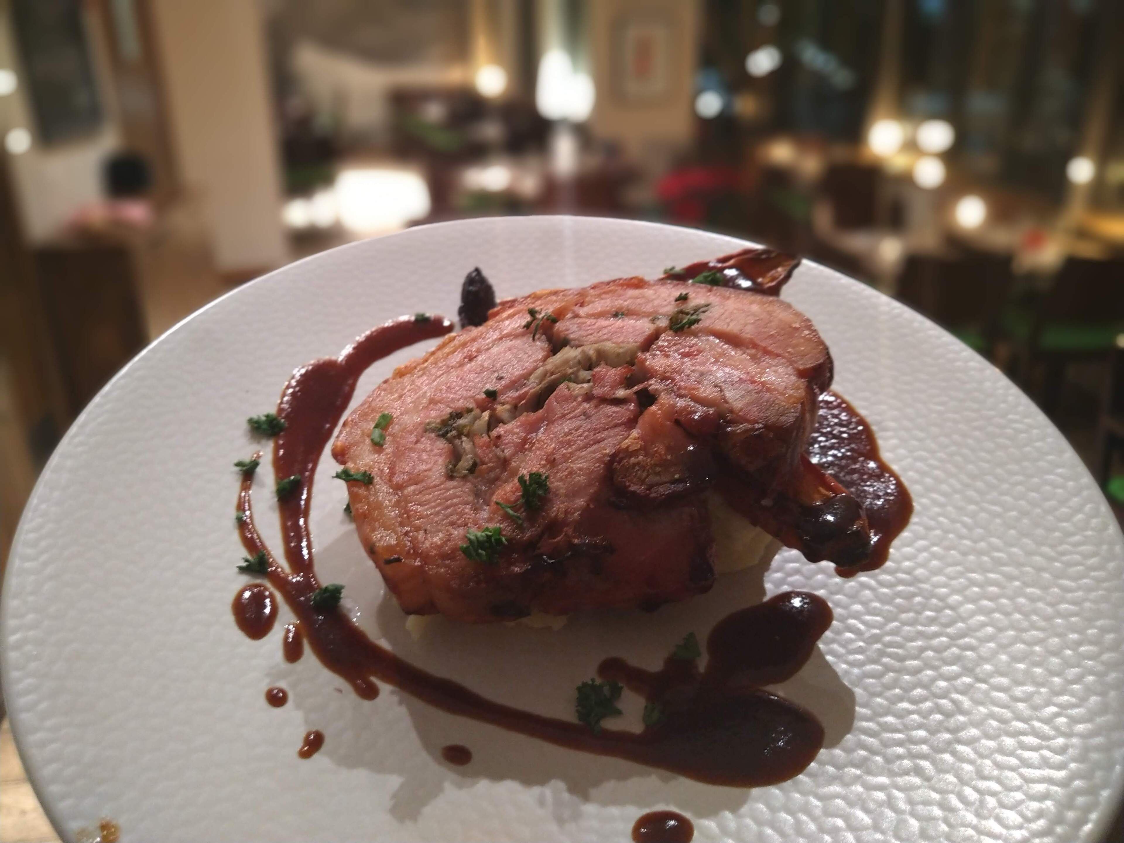 Un plato de comida con carne, decorado con hierbas y rociado con salsa.