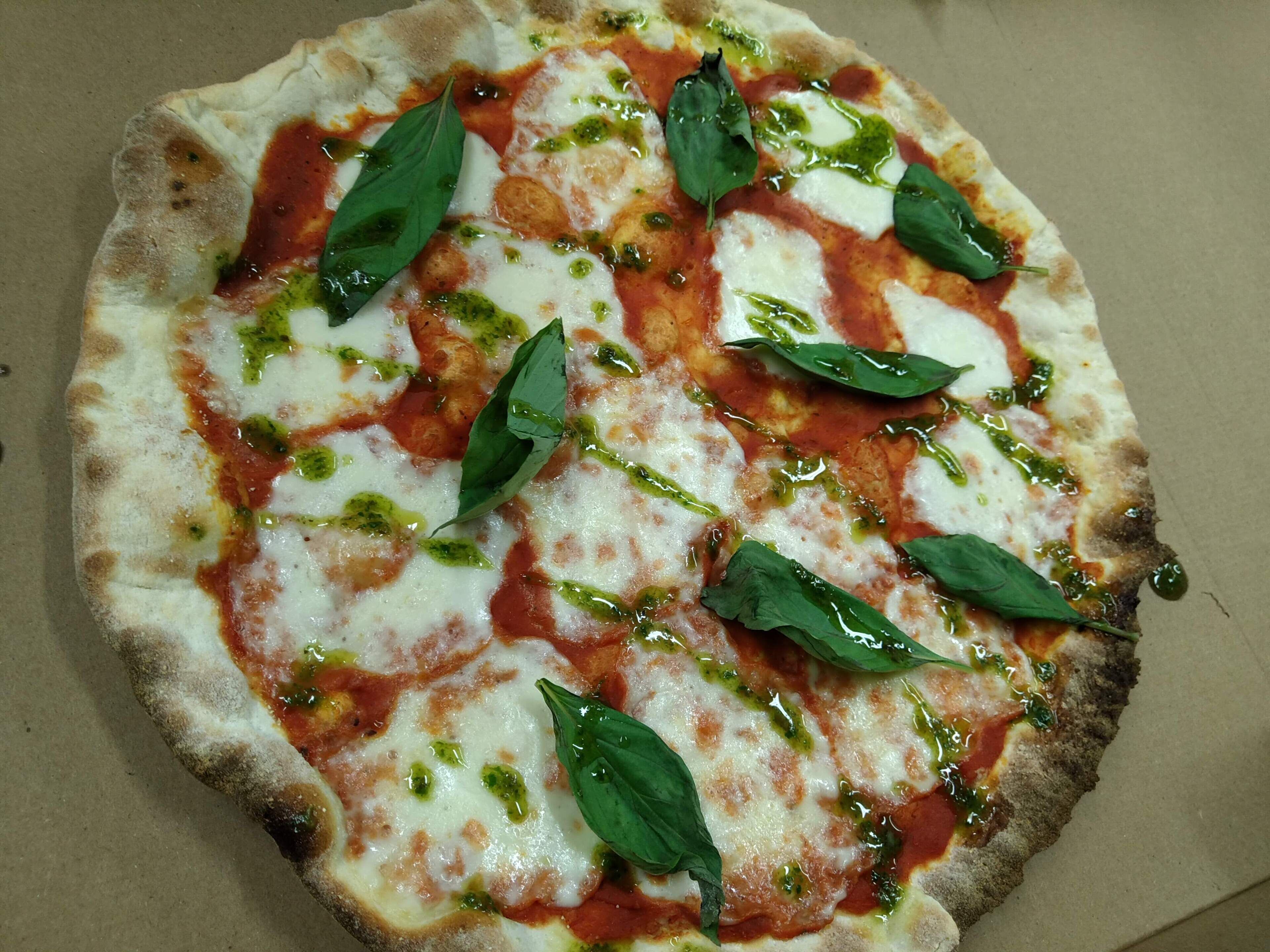Une pizza à la mozzarella, à la sauce tomate et aux feuilles de basilic.