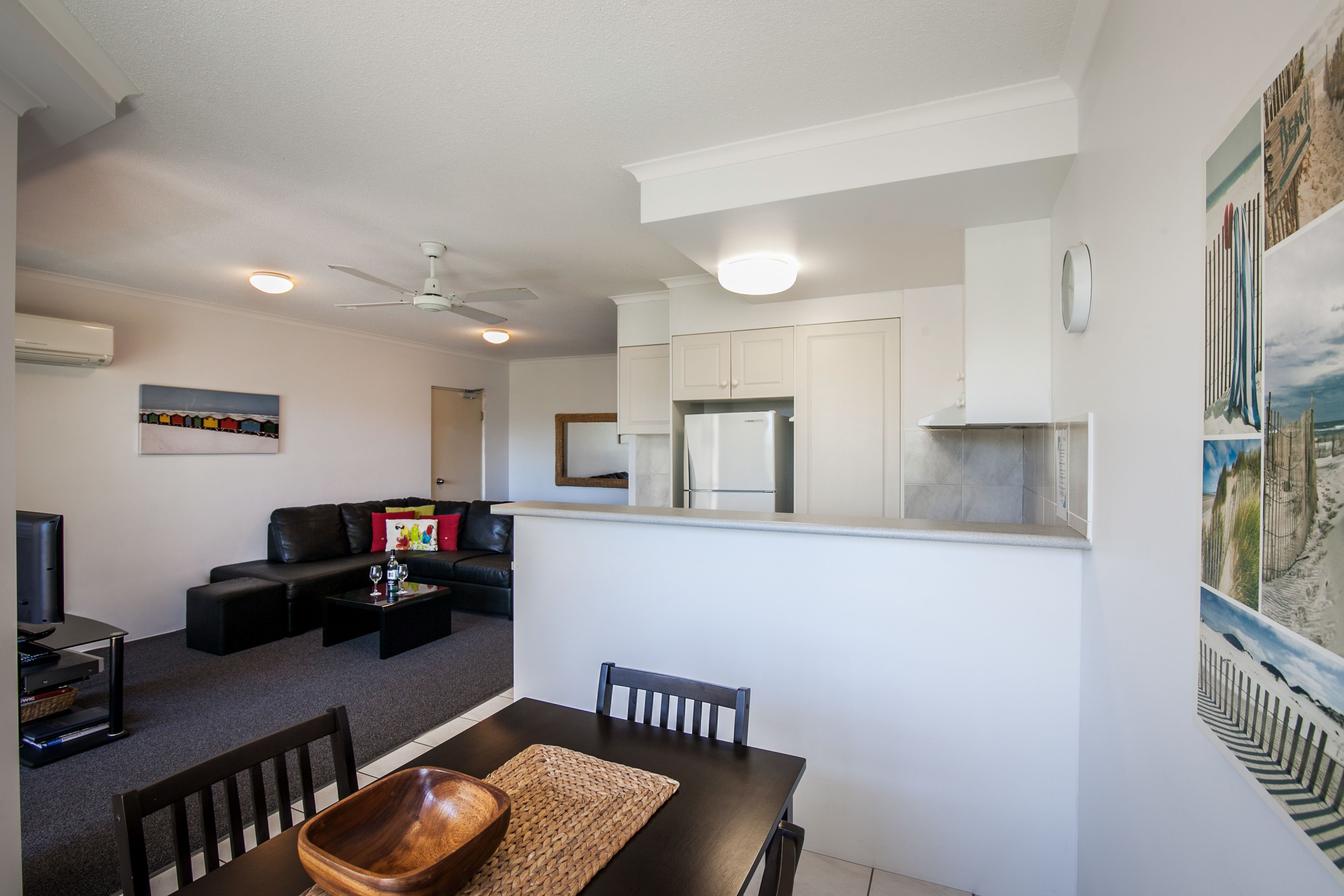 A modern living room with a sofa, coffee table, and a dining area with a wooden table and chairs.