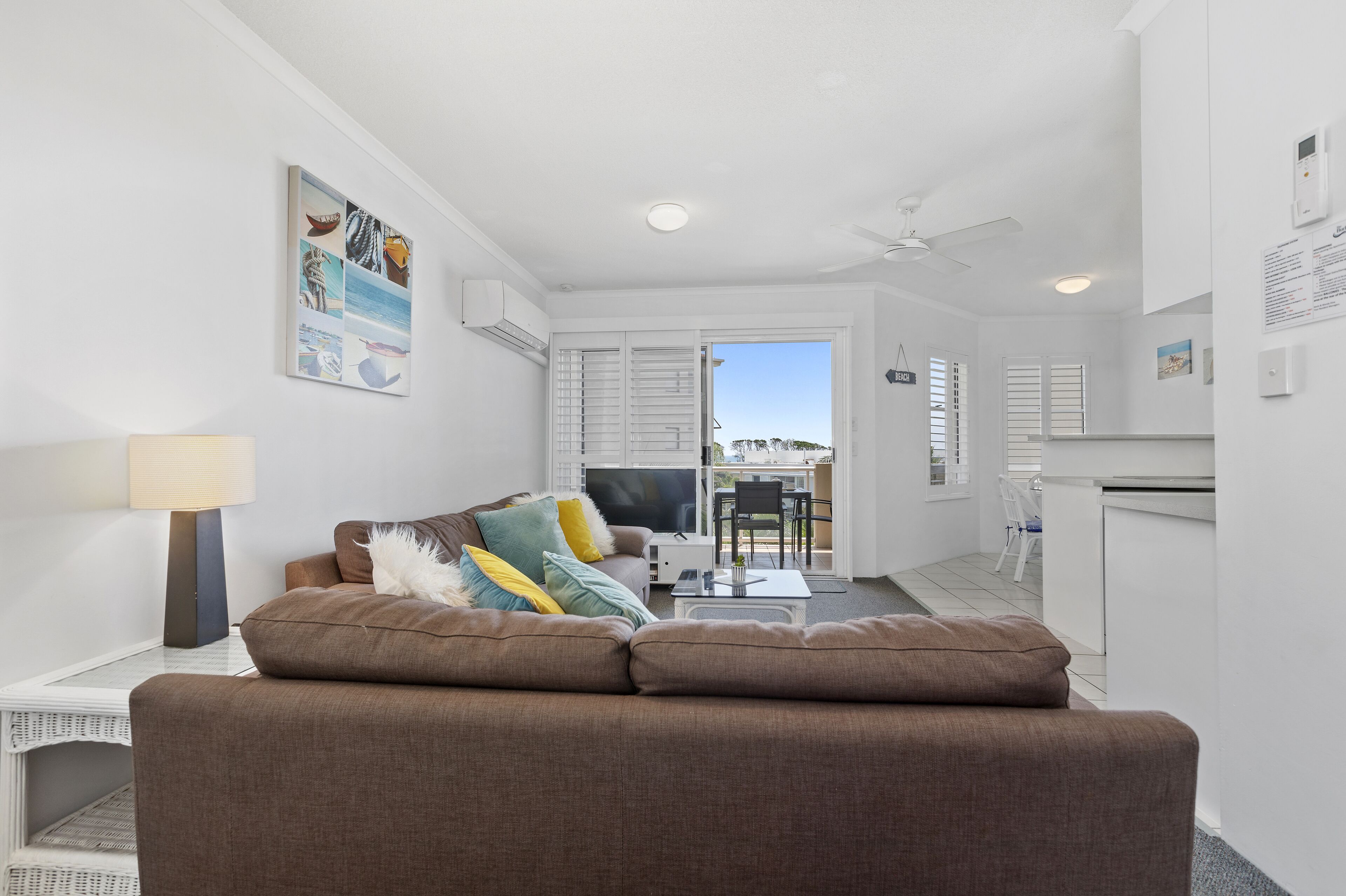 A modern living room with a sofa, a TV, and a dining area with a table and chairs.