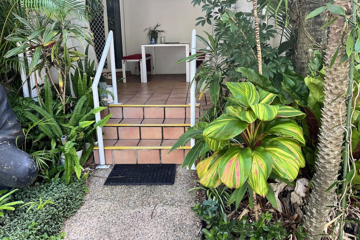 A garden entrance with a tiled pathway leading to a white door.