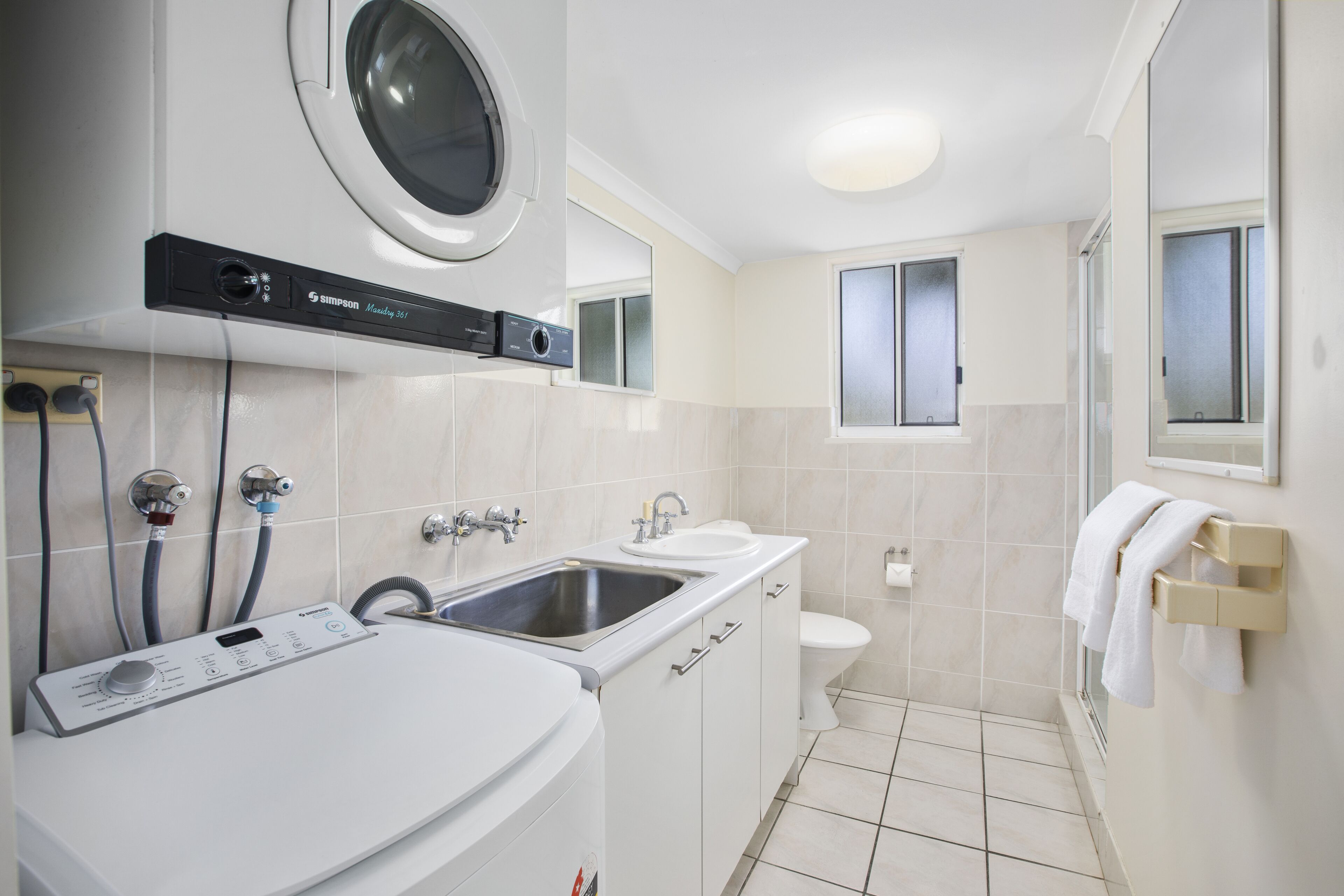 A modern bathroom with a built-in washing machine, a sink, and a toilet.