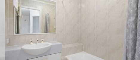 Ein Badezimmer mit Waschbecken, Spiegel und Badewanne.