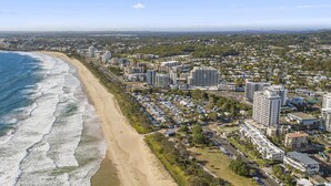 Vista aérea de una ciudad costera con playa, edificios altos y una zona urbana densa.