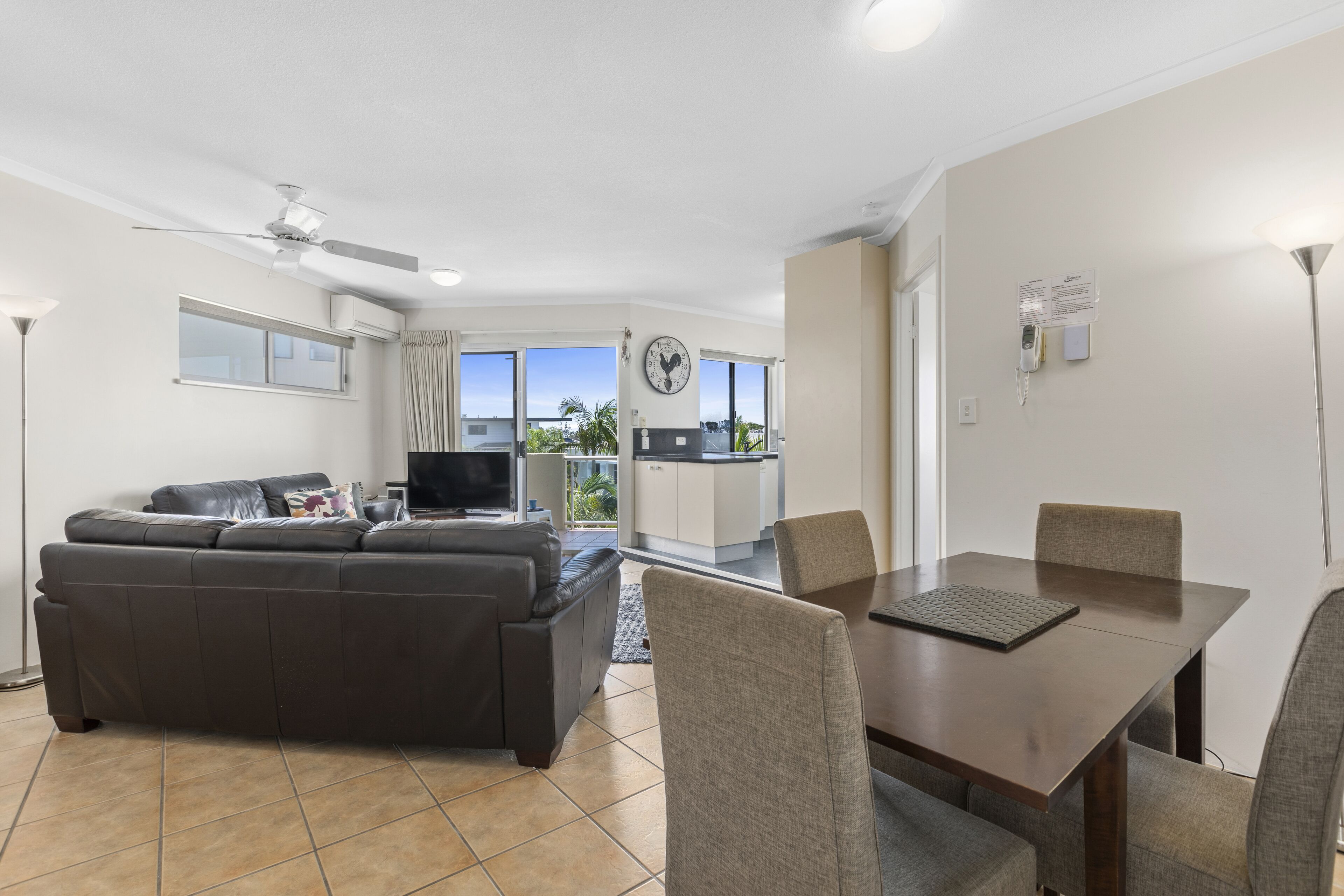 A modern living room with a sofa, TV, and dining area with chairs and a table.