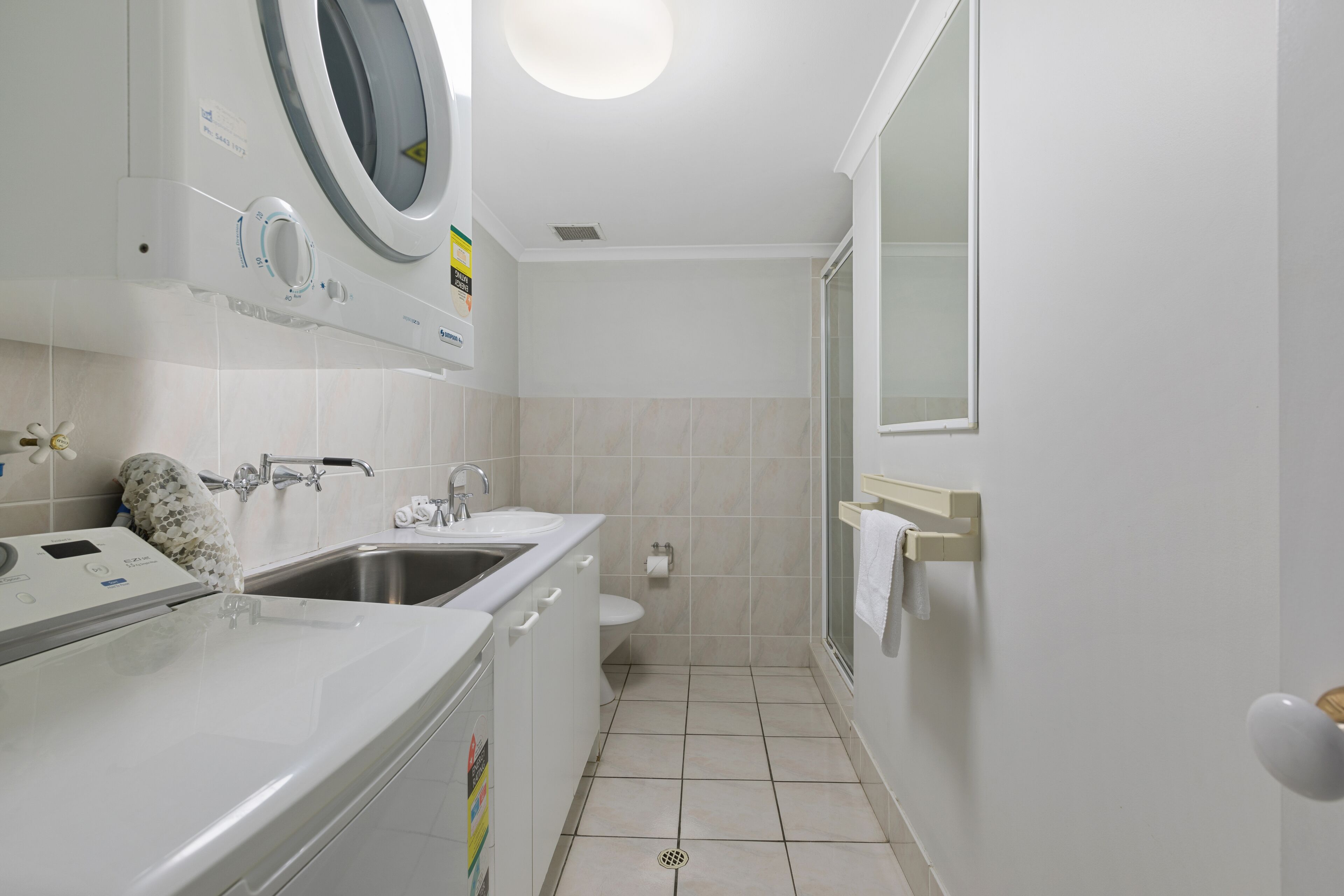 Une salle de bain moderne équipée d’un lave-linge intégré, d’un lavabo et de toilettes.