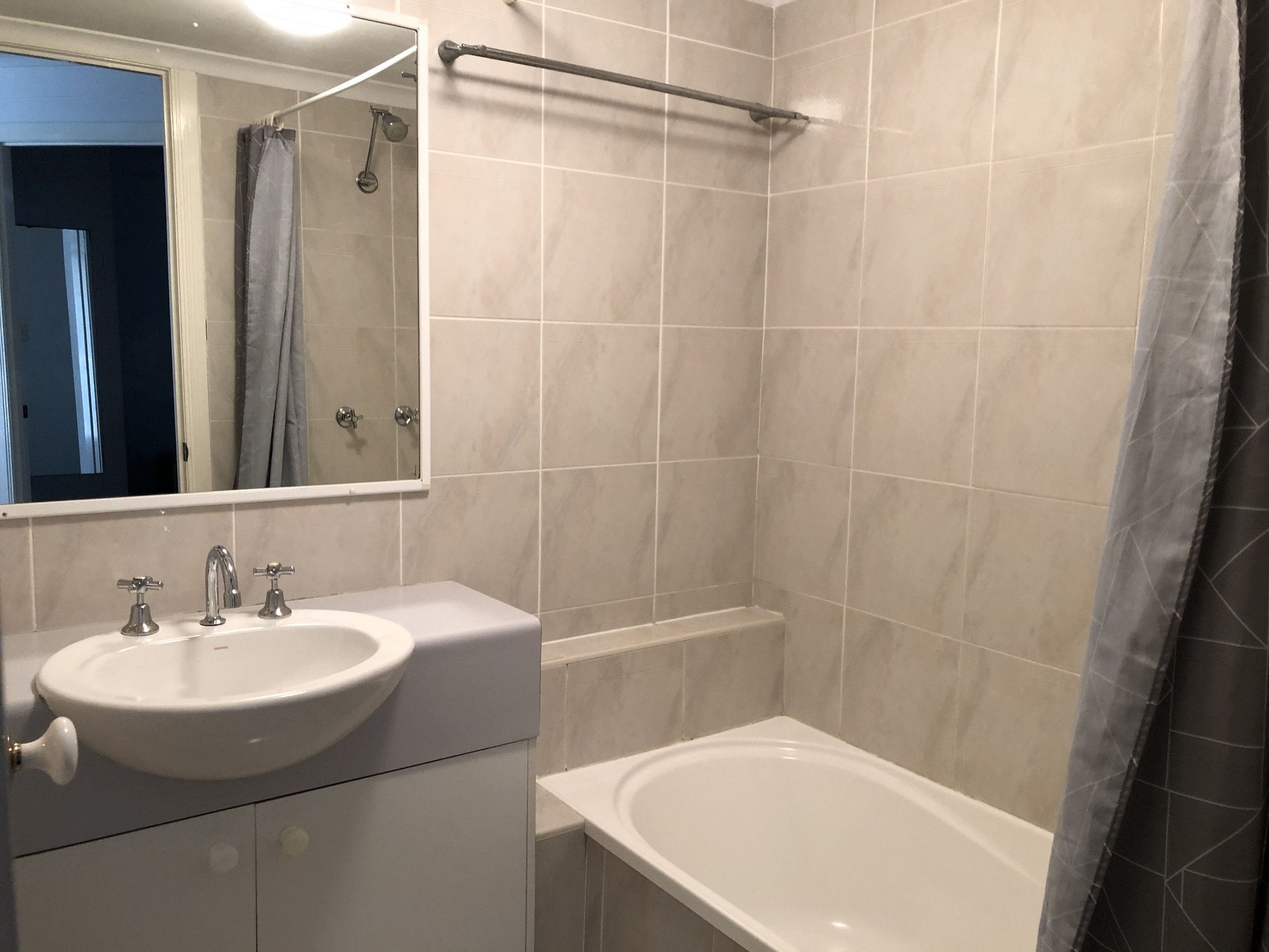 A bathroom with a sink, mirror, and bathtub.