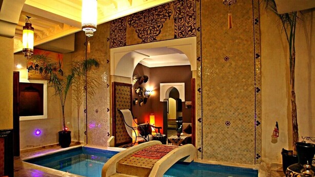 A luxurious indoor pool area with a central staircase, ornate wall designs, and ambient lighting. - Riad Sidi Mimoune (Marrakech)