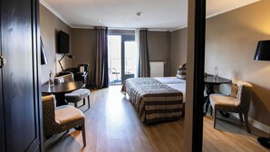 A hotel room with a bed, a desk, a chair, a table, a TV, and a view of the outdoors. - Hotel Gulpenerland  (Gulpen)