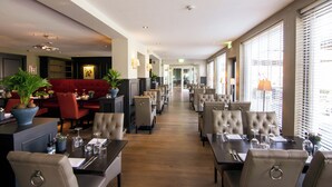 A hotel lobby with a long corridor, seating areas, and large windows. - Hotel Gulpenerland  (Gulpen)