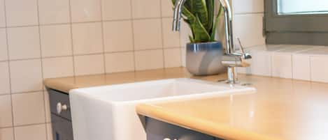 A kitchen with a sink, a potted plant, and a window.