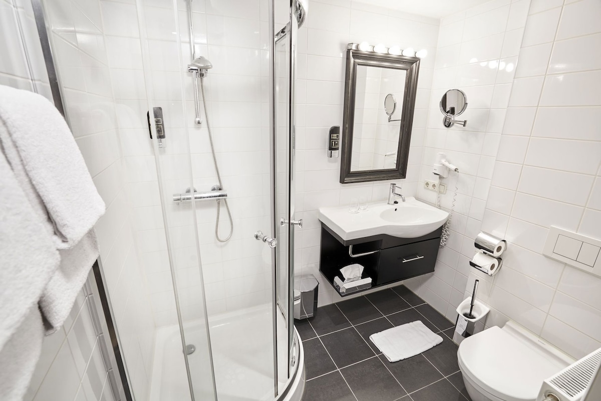 Un baño moderno con ducha de vidrio, tocador con espejo y retrete.