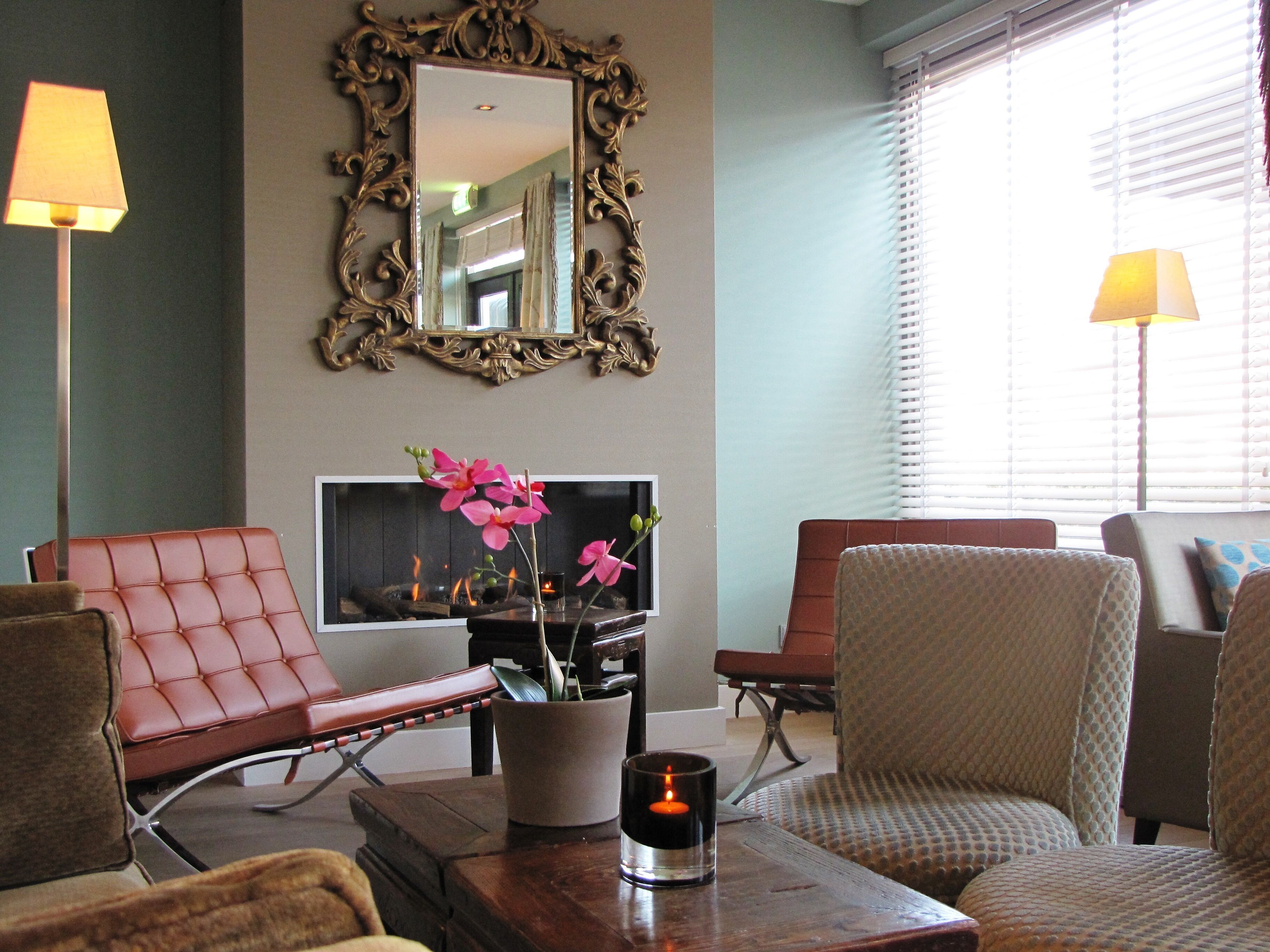 Un salon avec une cheminée, deux fauteuils, un canapé, une table basse et un lampadaire.