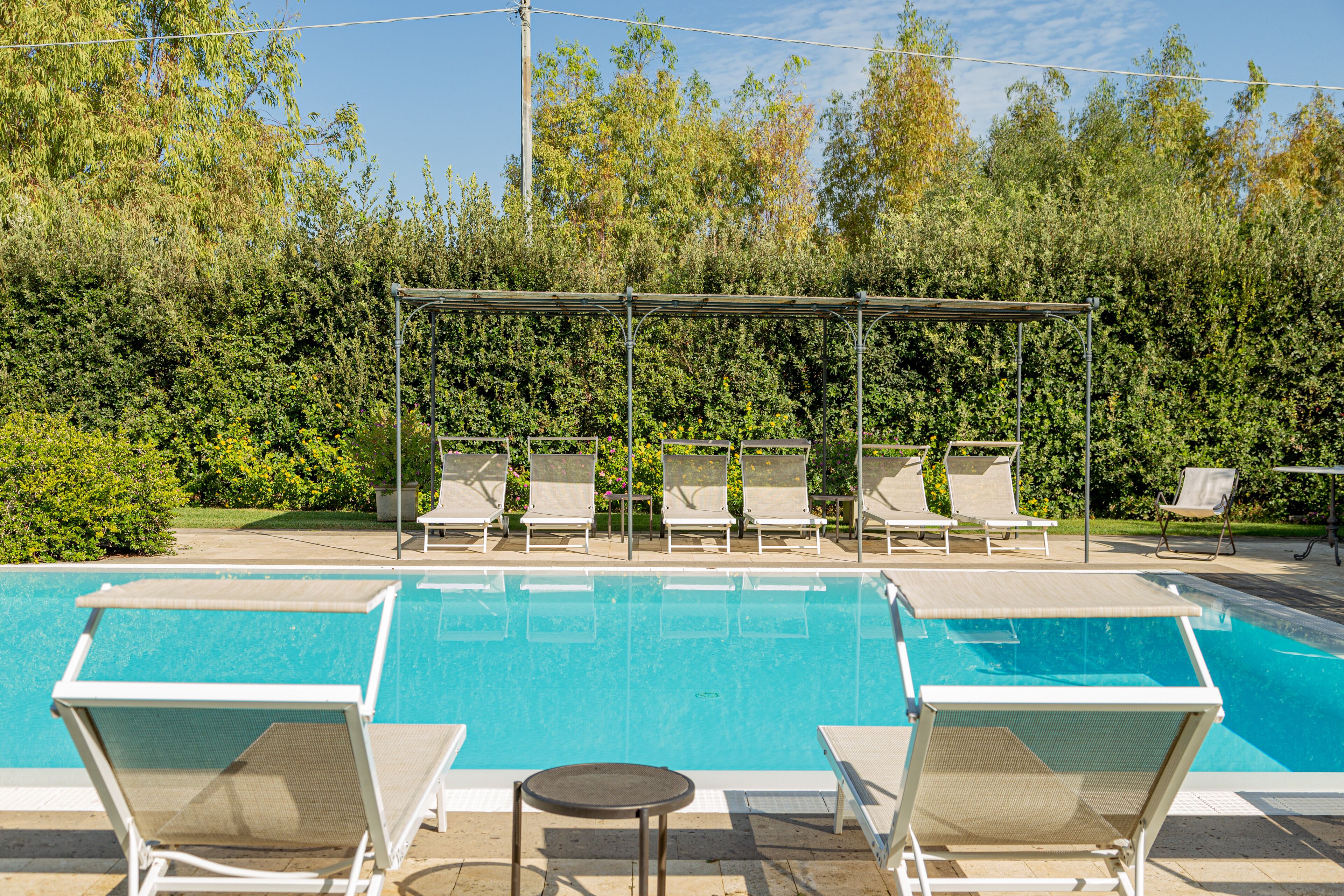 A swimming pool with lounge chairs and a covered seating area.