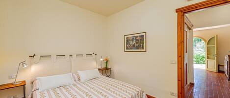 A bedroom with a bed, bedside table, lamp, and a painting on the wall.