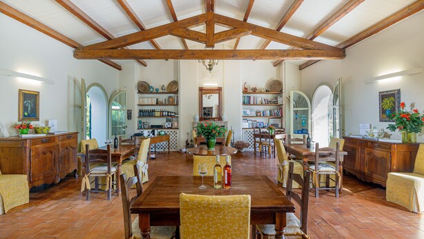 A spacious dining area with a wooden table and chairs, surrounded by bookshelves and decorative items. - Wine Resort Ledà d'Ittiri (Alghero)
