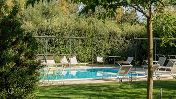Una piscina al aire libre, sillones reclinables de piscina