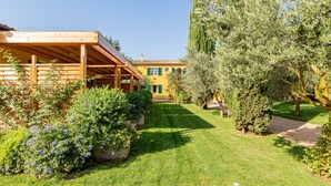 A wooden building with a covered patio area, surrounded by well-maintained lawns and various shrubs. - Wine Resort Ledà d'Ittiri (Alghero)