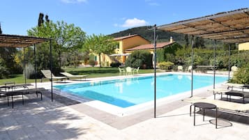 Una piscina al aire libre, sillones reclinables de piscina