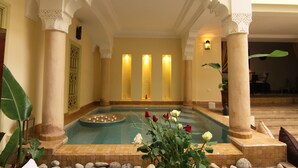 Un espace de bien-être comprenant une piscine, des colonnes et une composition florale.