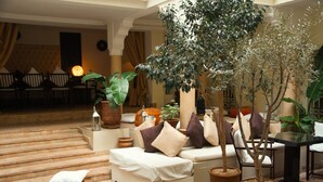 Un espace salon confortable avec un canapé, des fauteuils et des plantes en pot.